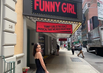 Lea Michele posing in front of the theater wearing black dress