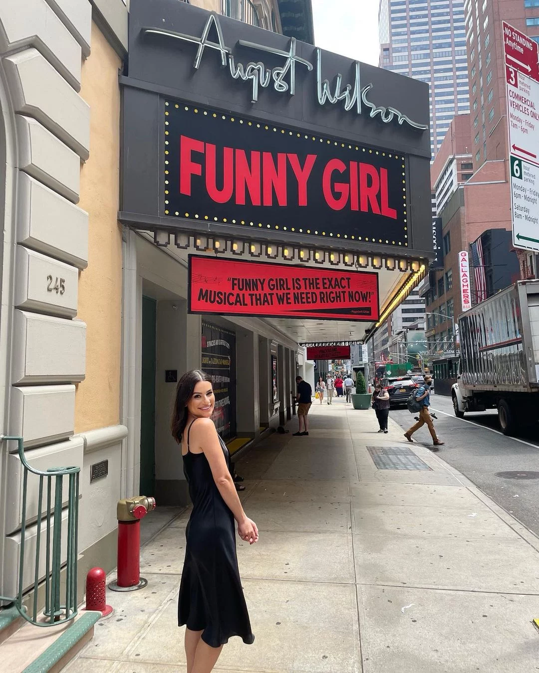 Lea Michele posing in front of the theater wearing black dress