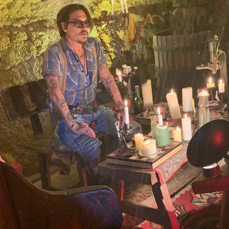 Johnny Depp sitting besides candles