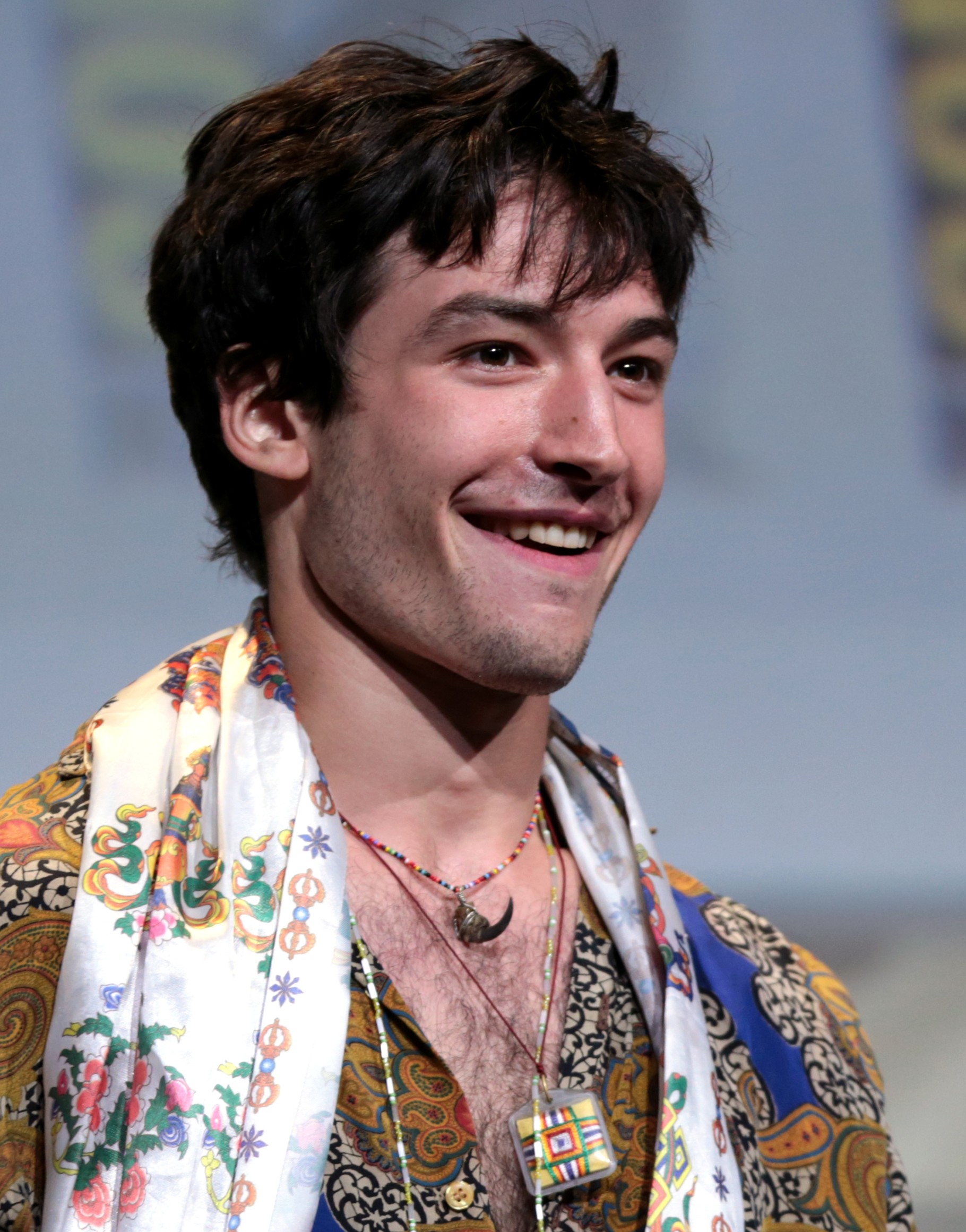 Ezra Miller wearing a white scarf and multi-colored shirt