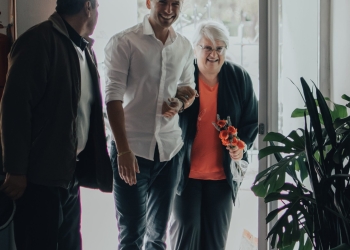 Elderly Woman and a Young Man Entering a Building Smiling