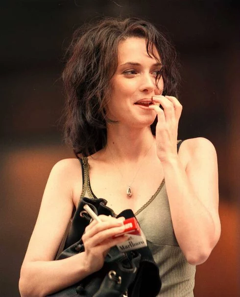 Winona Ryder wearing a tank top and holding cigarette in right hand.